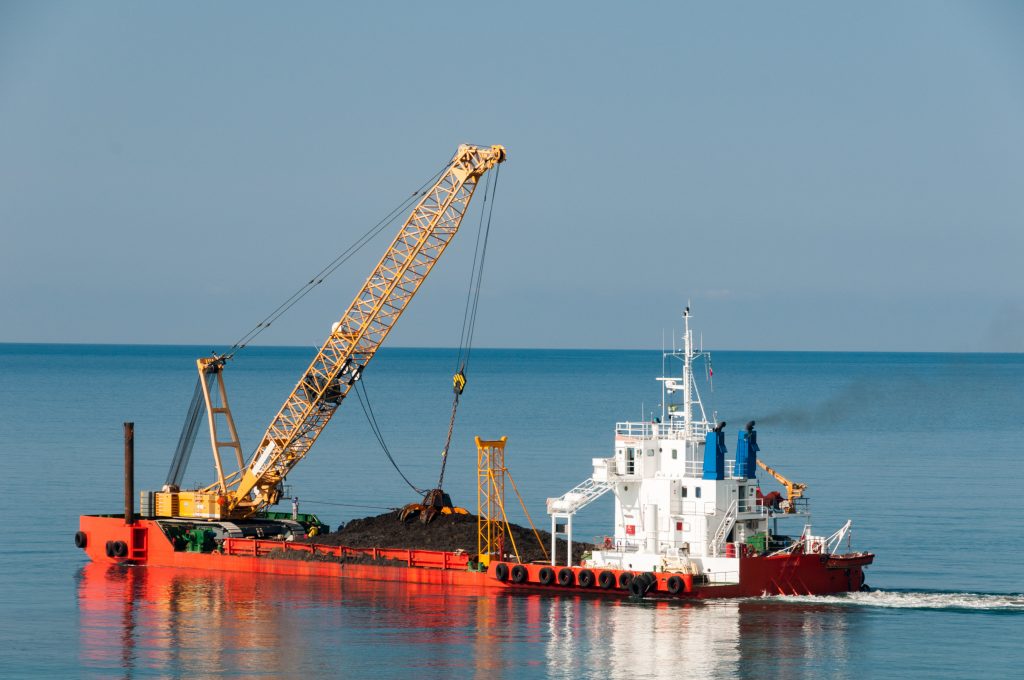 A ship is carrying a mining dredger.